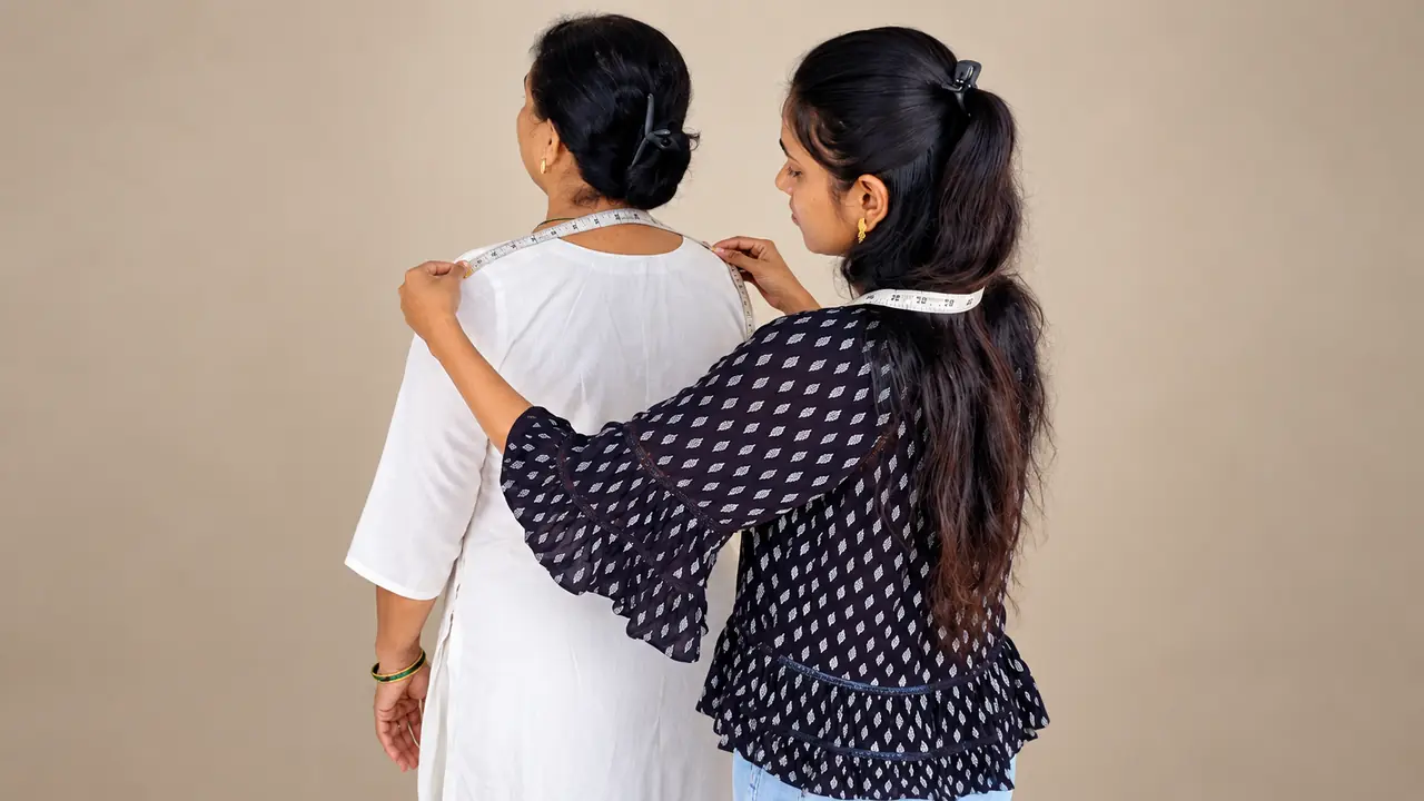 SACH Couture tailor measuring a client’s shoulder fit for garment alterations and resizing